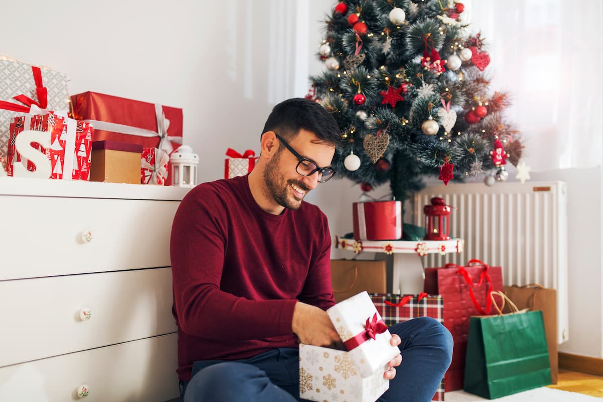 Man sitting on the floor opening up Christmas presents